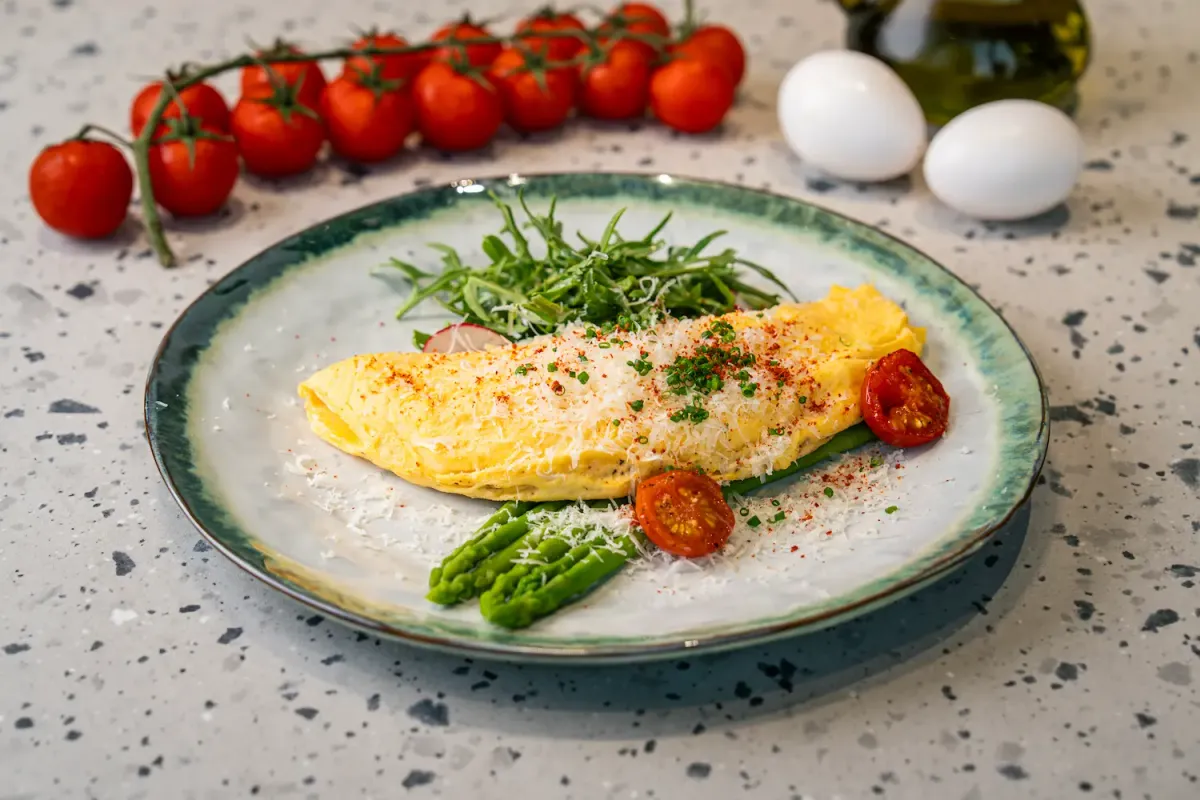 Folded omelette blanketed in finely grated parmesan and paprika, sat over asparagus spears with roasted tomato halves and rocket