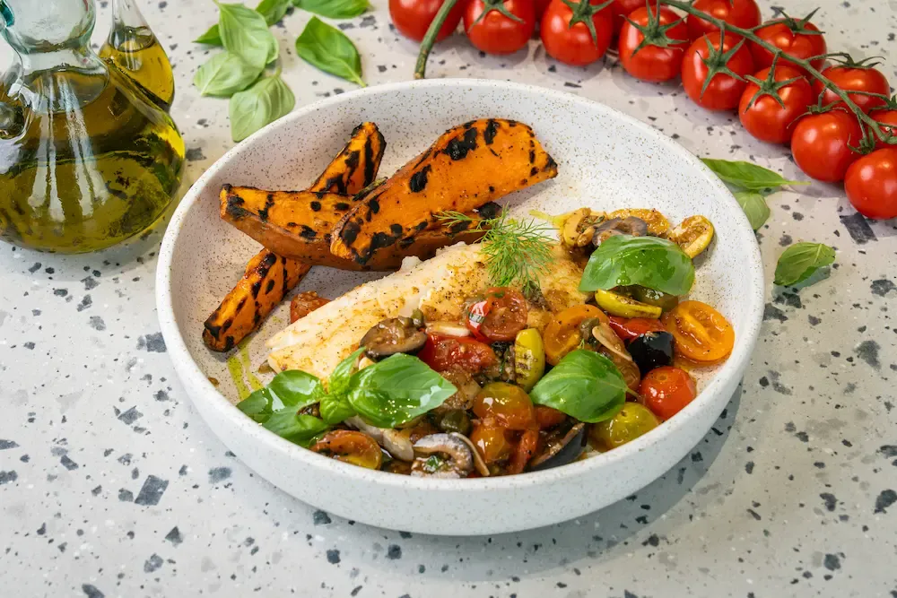 White cod fillet with charred sweet potato wedges and a chunky tomato, olive and caper salsa, scattered with basil leaves