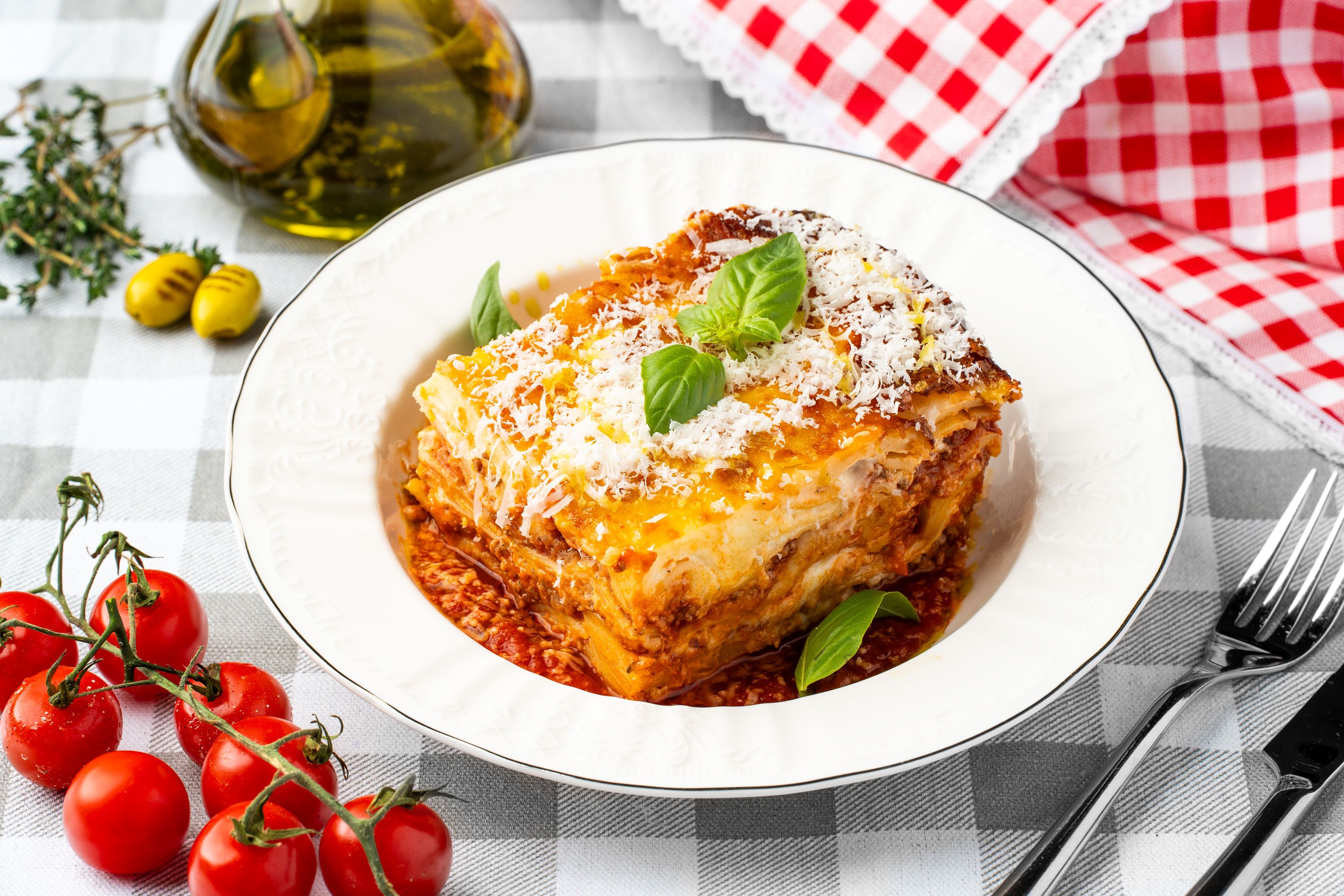 A layered baked pasta portion with tomato sauce, grated cheese and basil