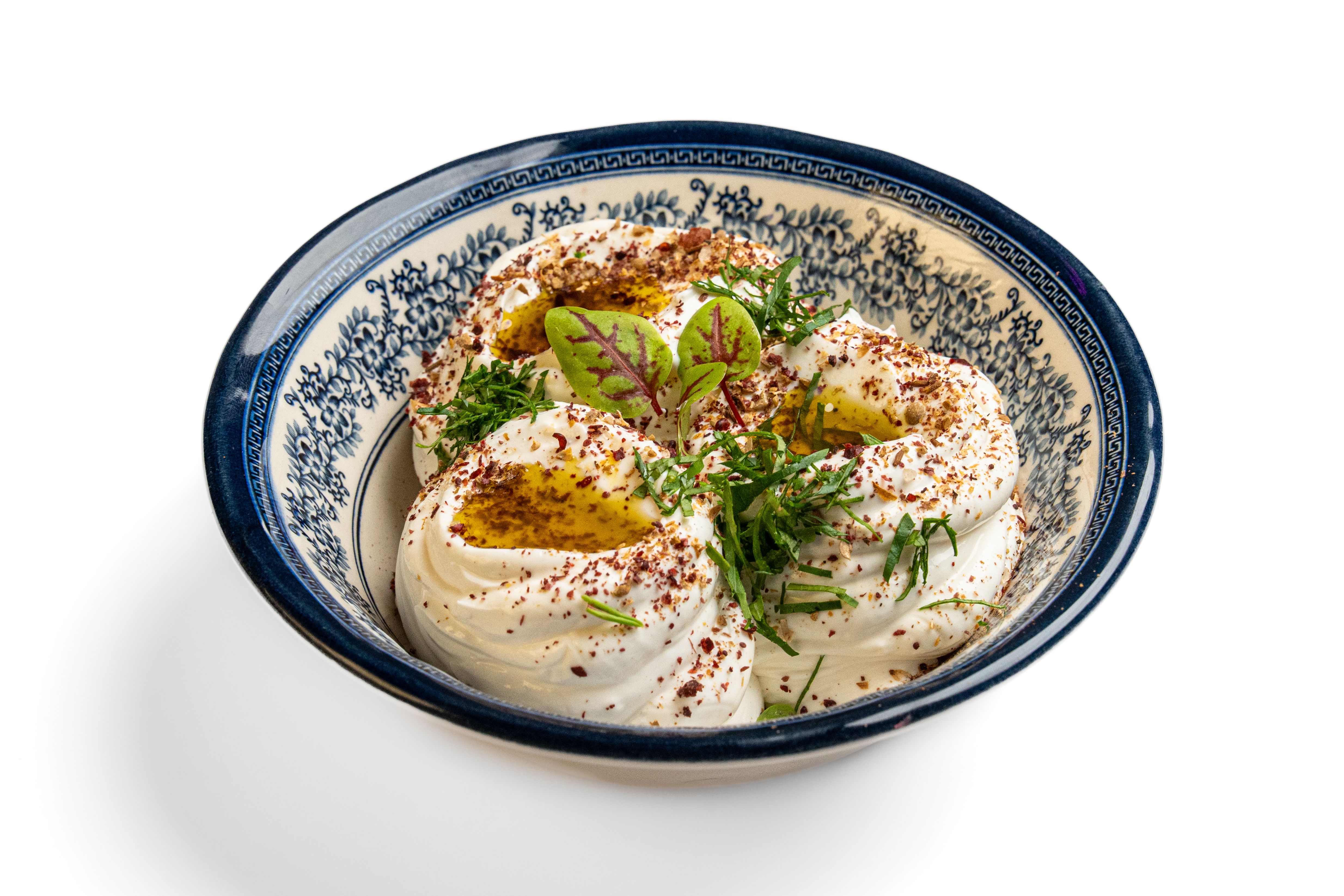 A creamy dip finished with herbs and olive oil in a patterned bowl