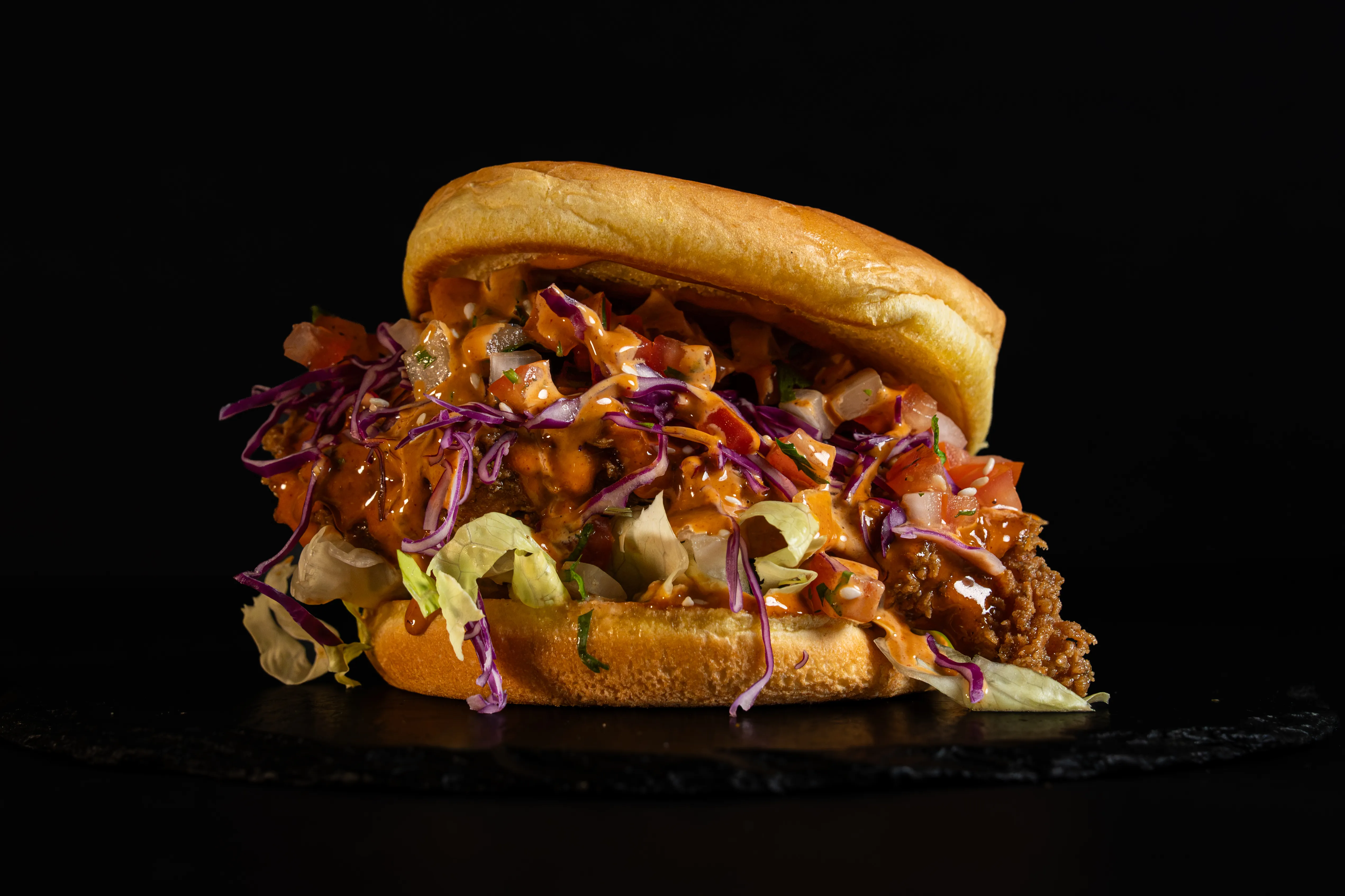 A chicken burger layered with purple slaw and sauce