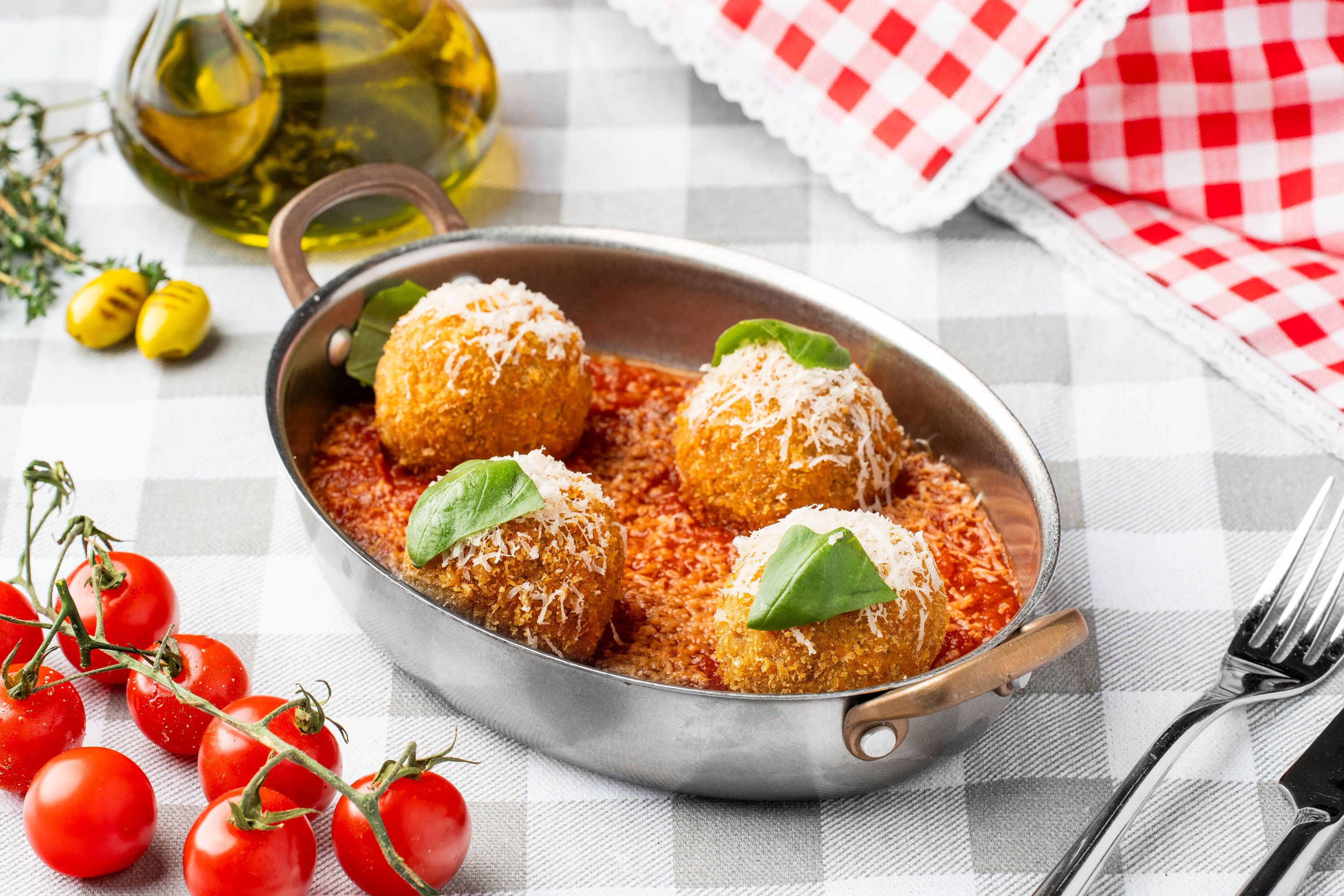 Golden crumbed bites in a handled pan with tomato sauce and basil