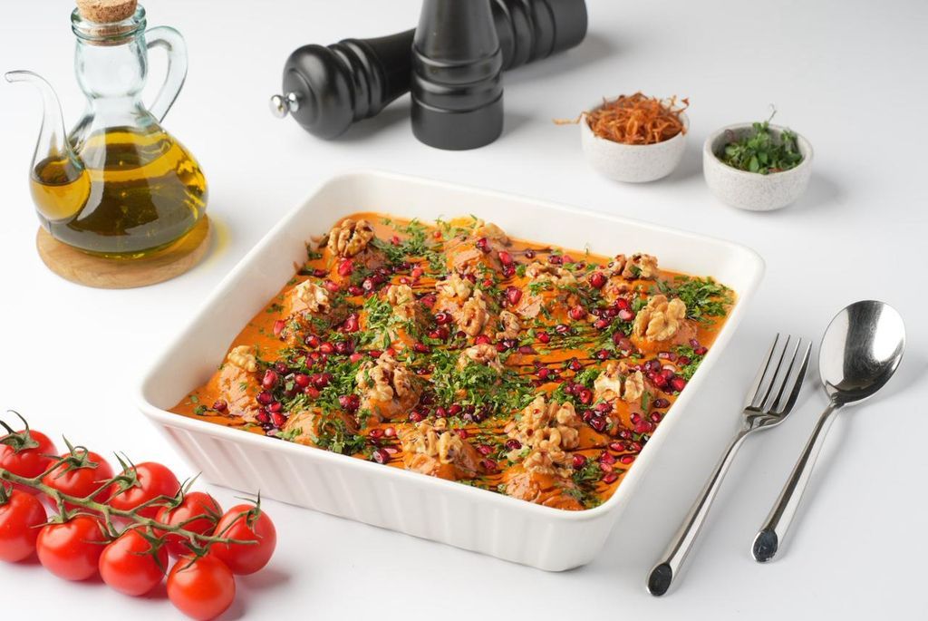A sharing dish of lamb kibbeh with walnut sauce, parsley and bright pomegranate seeds