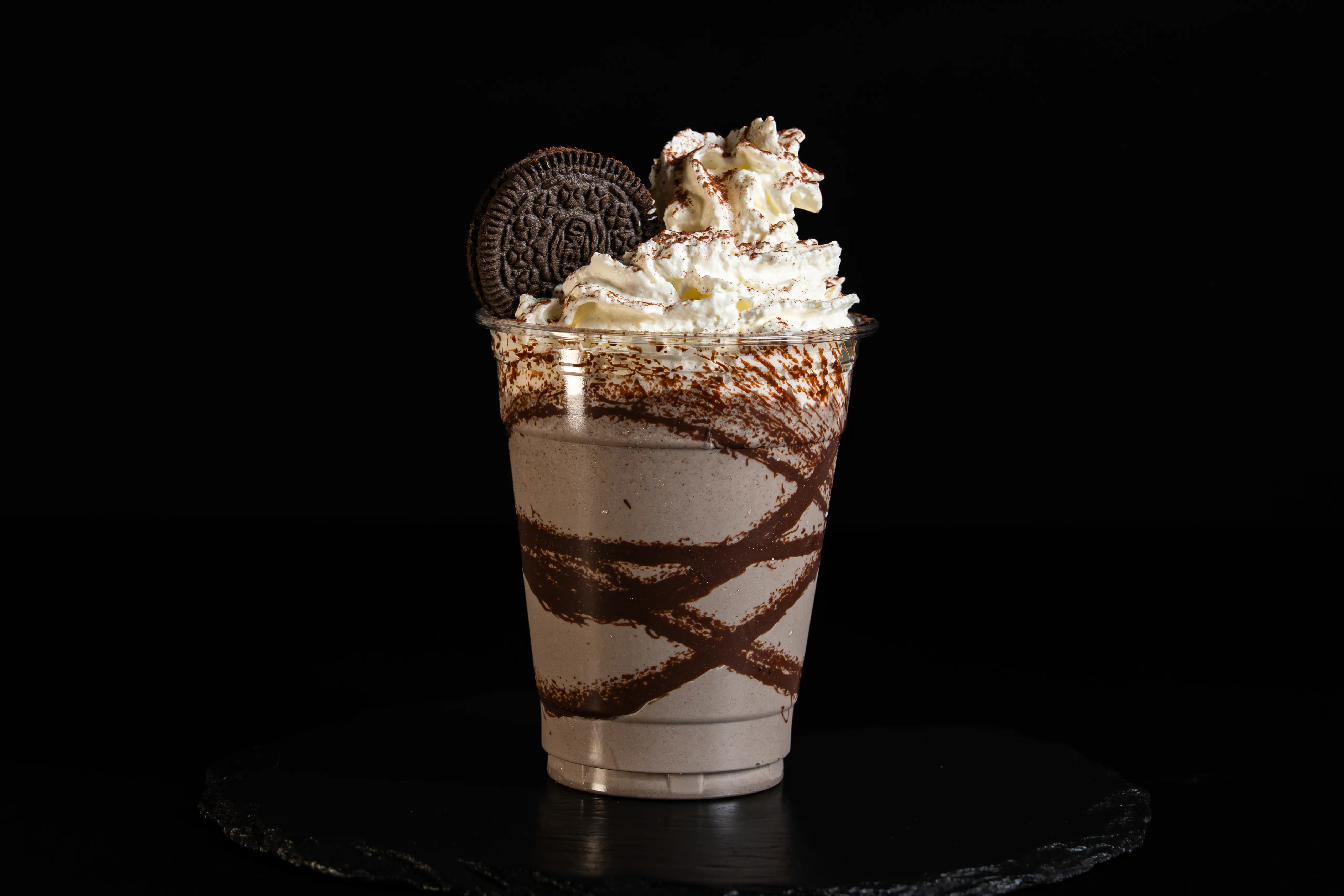 A tall chocolate-striped milkshake topped with cream and cookies