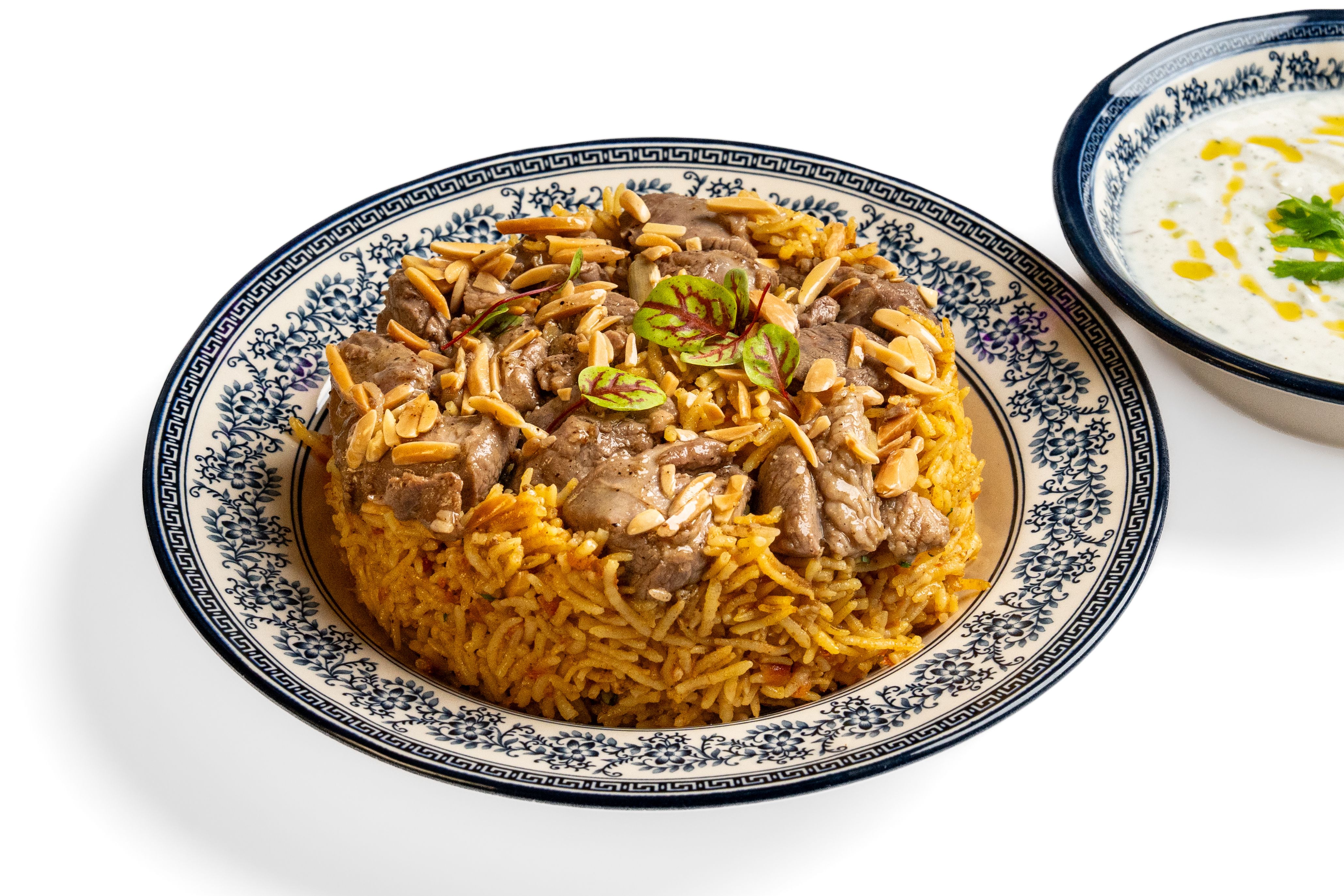 Golden rice topped with meat and toasted nuts on a patterned blue plate