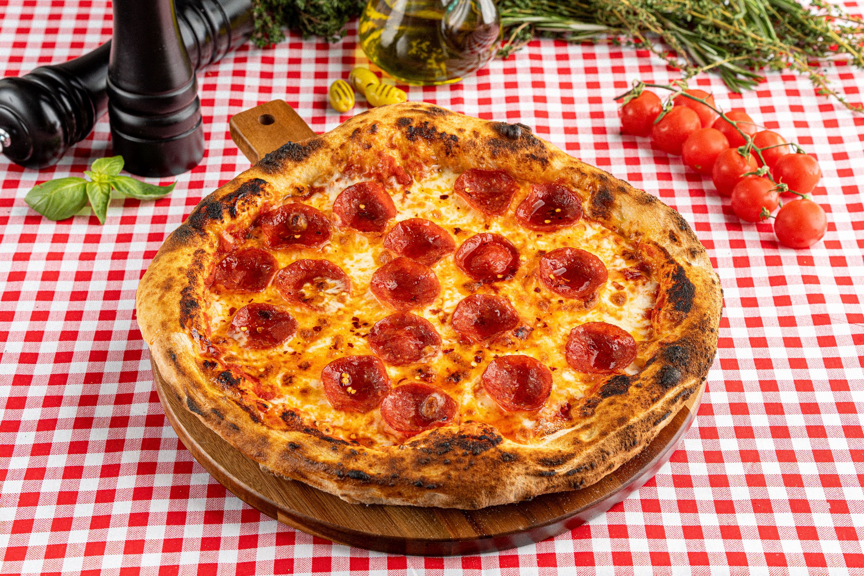 A blistered pizza topped with cheese and rounds of sausage
